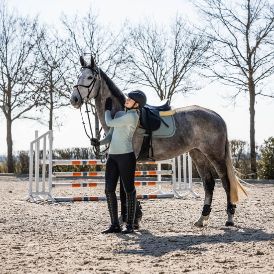 Person wearing HKM Supersoft II Functional 1/4 Zip Shirt in sage next to a horse