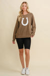 Woman wearing a brown sweater with a white horseshoe design on a beige background - equestrian fashion outfitters