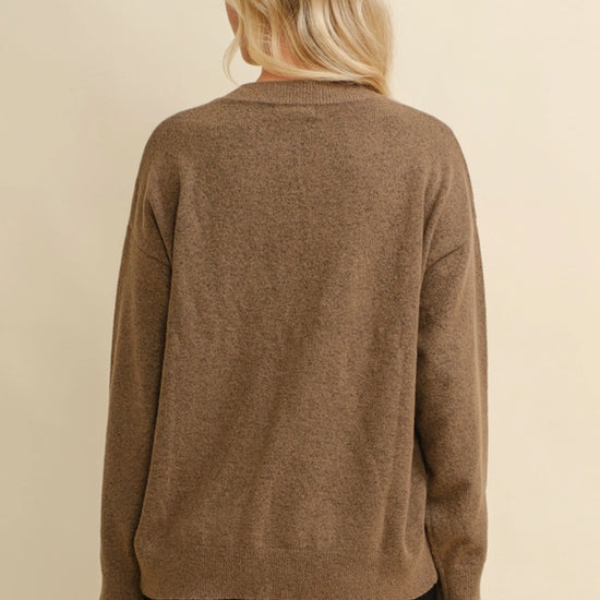 Woman wearing a brown sweater with a white horseshoe design on a beige background - equestrian fashion outfitters