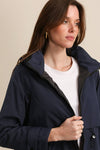 Woman wearing a navy blue jacket over a white shirt against a beige background equestrian fashion outfitters
