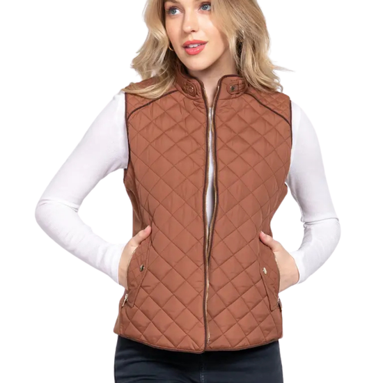 A woman modeling a brown diamond-quilted zip-up vest over a white long-sleeve top and dark pants, photographed against a plain white background. equestrian fashion outfitters