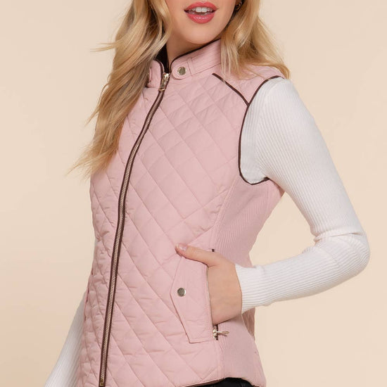 Woman wearing a pink quilted vest against a beige background equestrian fashion outfitters