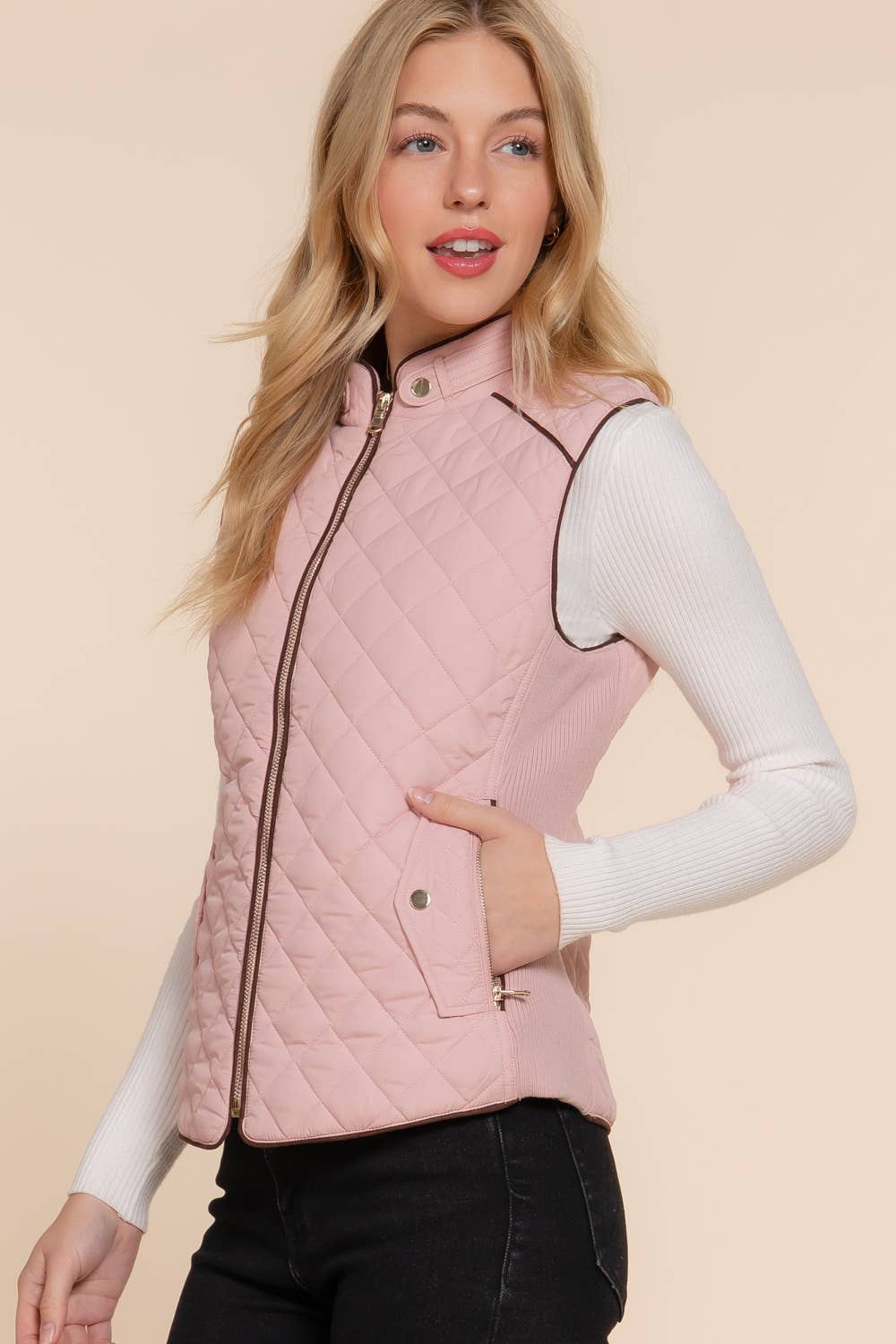 Woman wearing a pink quilted vest against a beige background equestrian fashion outfitters