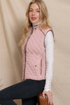 Woman wearing a pink quilted vest against a beige background equestrian fashion outfitters