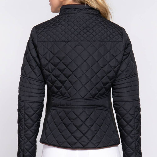 Person wearing a black quilted jacket on a white background equestrian fashion outfitters