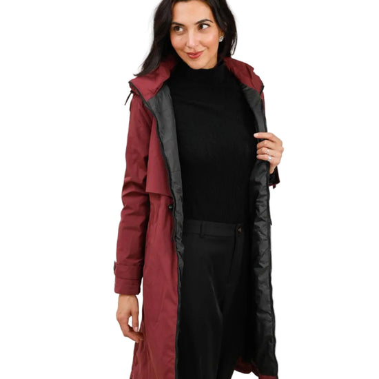 Woman wearing a long red and black rain coat on a white background equestrian fashion outfitters