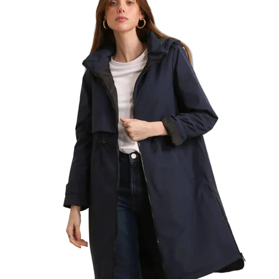 Woman wearing a navy blue coat over a white shirt and dark jeans on a white background equestrian fashion outfitters