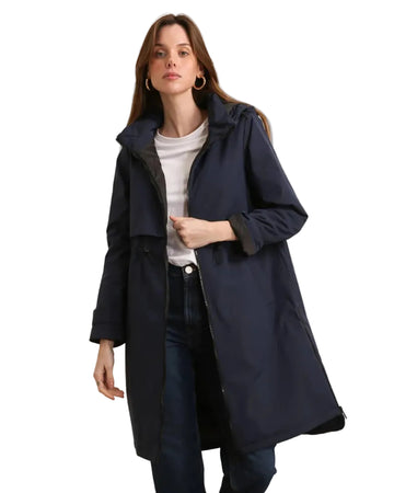 Woman wearing a navy blue coat over a white shirt and dark jeans on a white background equestrian fashion outfitters