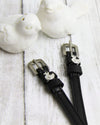 Black Spur Straps with a duck silver buckles on a light wooden surface.