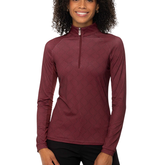 A woman with curly black hair wearing a long-sleeve, quarter-zip athletic top in a textured burgundy oxblood herringbone color, paired with breeches pants,equestrian fashion outfitters