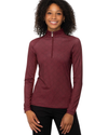A woman with curly black hair wearing a long-sleeve, quarter-zip athletic top in a textured burgundy oxblood herringbone color, paired with breeches pants,equestrian fashion outfitters