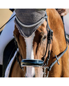 A close-up of a brown horse wearing a dark gray mesh protective headband or blind with silver trim, along with a black bridle with white padding on the nose and a patent noseband equestrian fashion outfitters