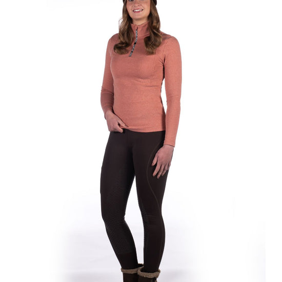 Woman wearing a pink HKM long-sleeve top, HKM black leggings, and brown boots on a white background