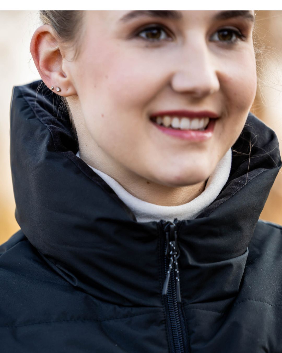Close-up of a woman wearing a black  HKM vest with a blurred background