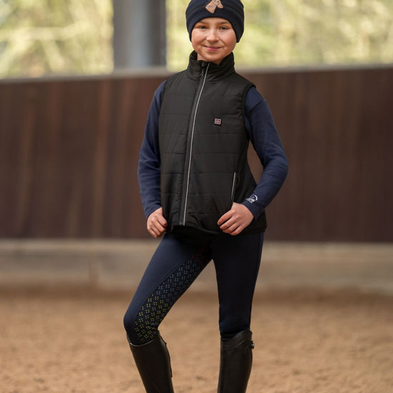 Child wearing HKM kids Black heated vest  and headband on neutral background equestrian fashion outfitters