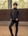 Child wearing HKM kids Black heated vest  and headband on neutral background equestrian fashion outfitters