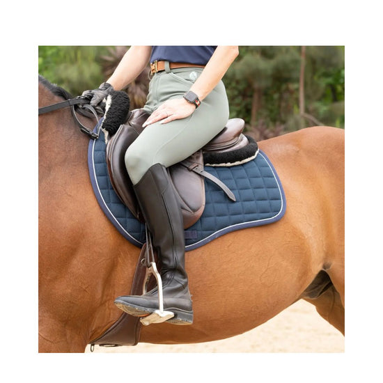 Person riding a horse with a blue saddle pad on a natural background