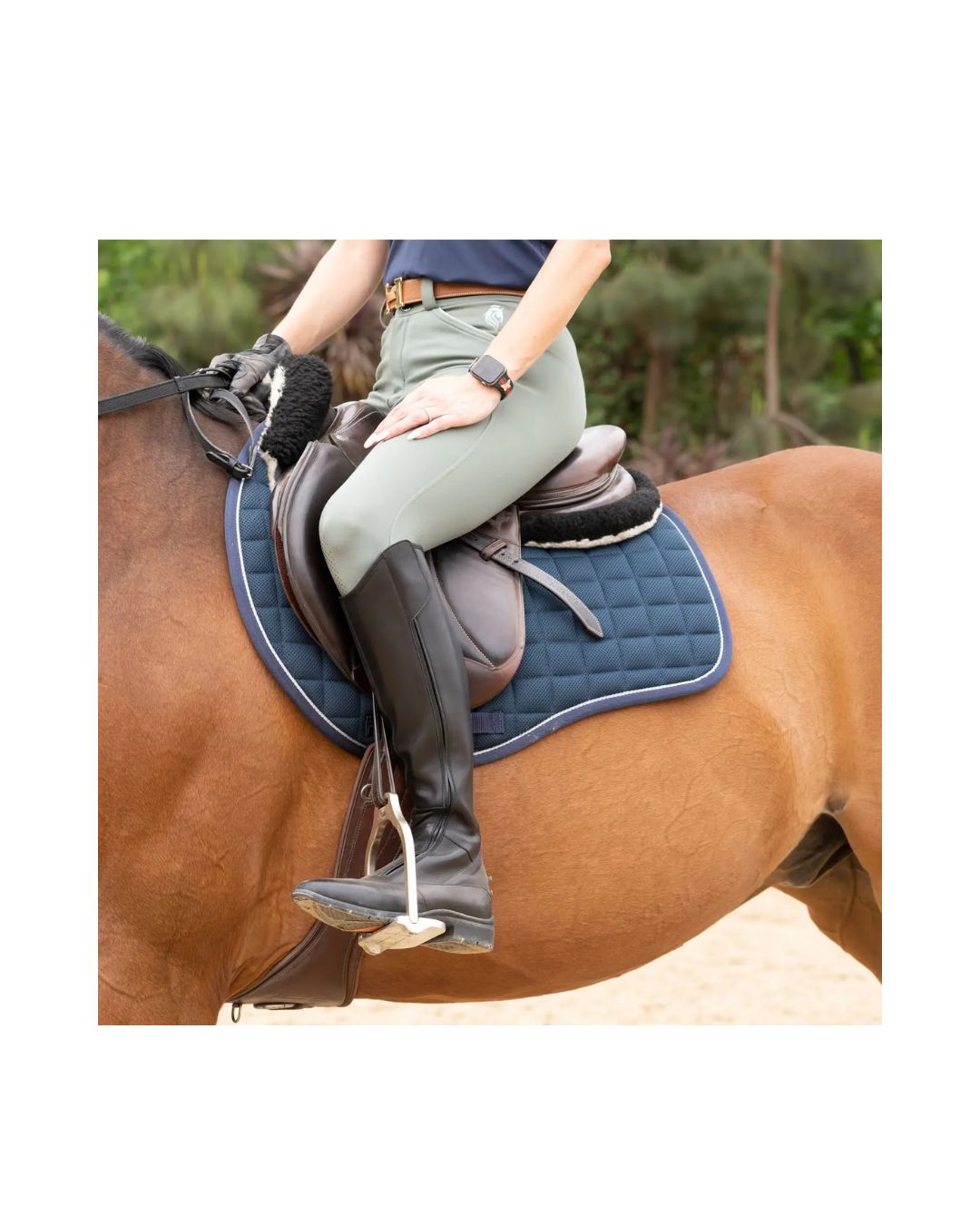Person riding a horse with a blue saddle pad on a natural background