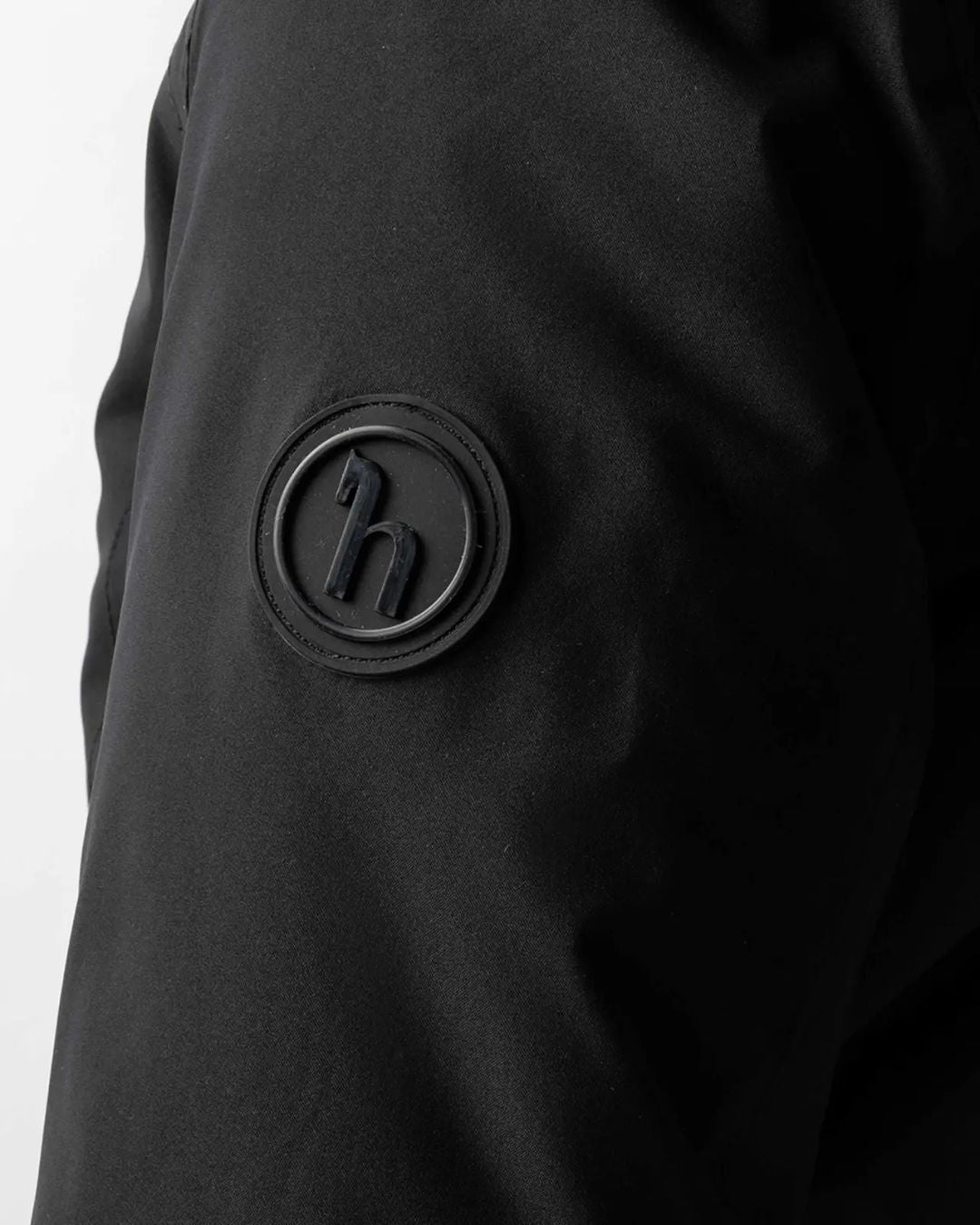 Black jacket with a logo patch on a white background