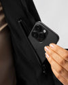 Person holding a black phone case with an inside pocket against a neutral background