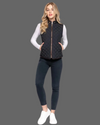 Woman wearing a black quilted vest over a white long-sleeve shirt on a white background equestrian fashion outfitters