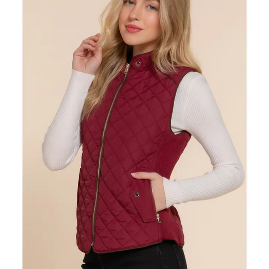 Woman wearing a red quilted vest against a beige background equestrian fashion outfitters