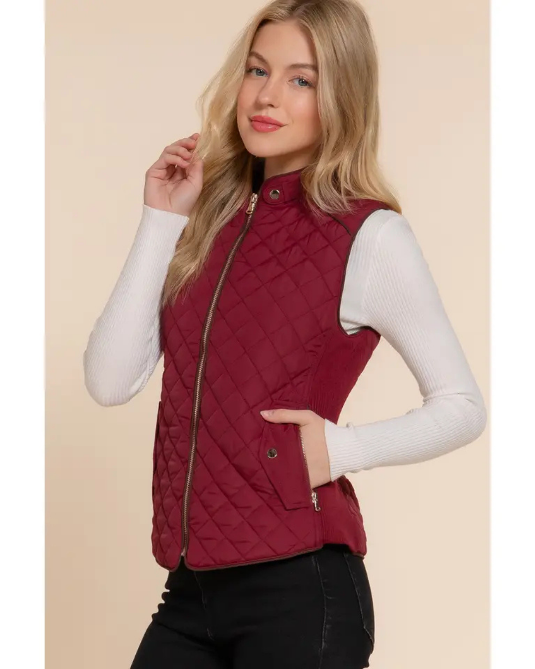 Woman wearing a red quilted vest against a beige background equestrian fashion outfitters