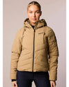Woman wearing a beige puffer jacket with a brand logo on a plain background