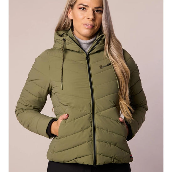 Woman wearing a green puffer jacket with a neutral background