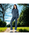 Woman in a denim outfit standing on a path with trees and blue sky in the background