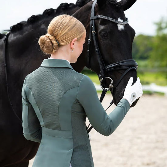 Woman in equestrian attire standing next to a horse in an outdoor setting equestrian fashion outfitters