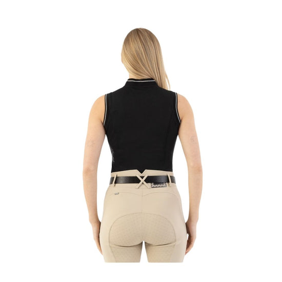 Woman wearing beige riding pants with a black belt and black sleeveless polo on a white background equestrian fashion outfitters