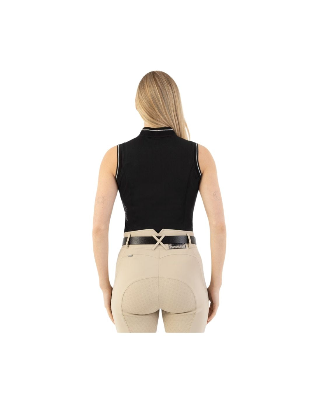 Woman wearing beige riding pants with a black belt and black sleeveless polo on a white background equestrian fashion outfitters