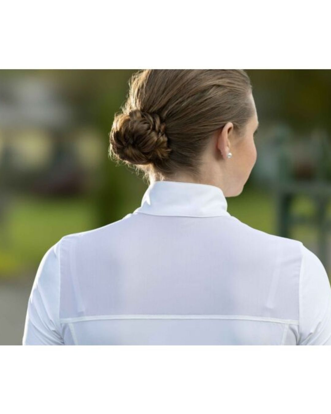 Person wearing a white shirt with a blurred outdoor background Equestrian fashion outfitters