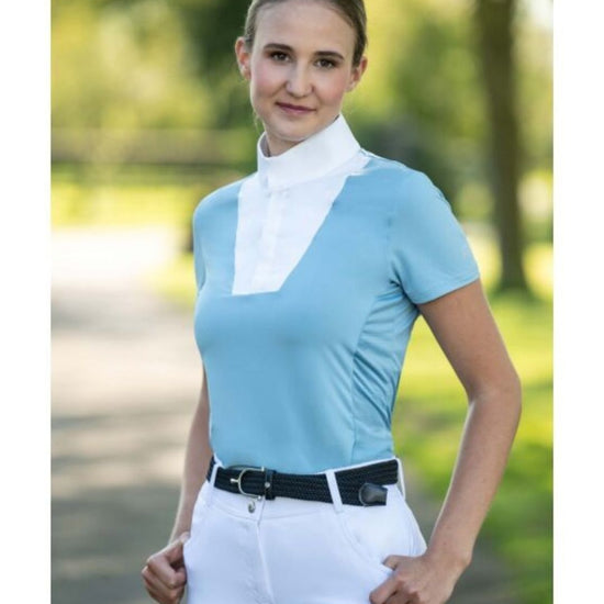 Woman wearing a light blue equestrian shirt with a white collar and white pants outdoors. Equestrian fashion outfitters