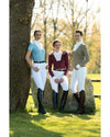 Three women in equestrian attire standing outdoors with a tree and hay bale in the background. Equestrian fashion outfitters