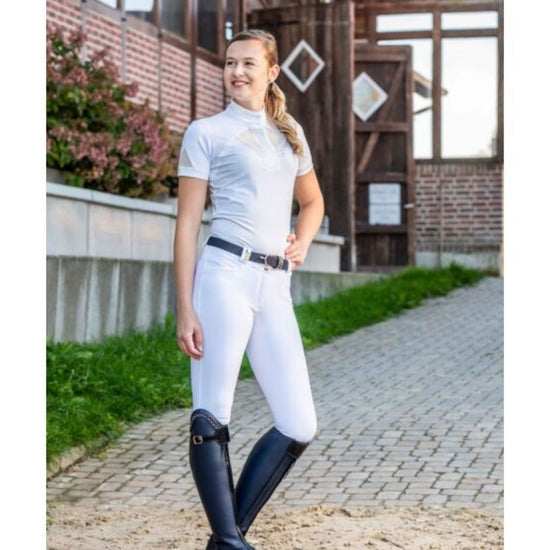 Woman in equestrian attire standing on a path with a building in the background Equestrian fashion outfitters