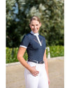 Woman wearing a navy equestrian shirt with white accents and white pants outdoors. Equestrian fashion outfitters