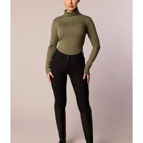 Person wearing a green turtleneck and black pants on a plain background