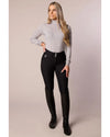 Woman wearing a gray turtleneck and black riding pants on a beige background