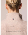 Back view of a person wearing a beige equestrian jacket with a brand logo on a plain background