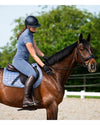Woman riding a brown horse in an outdoor equestrian setting grey blue tights equestrian fashion outfitters