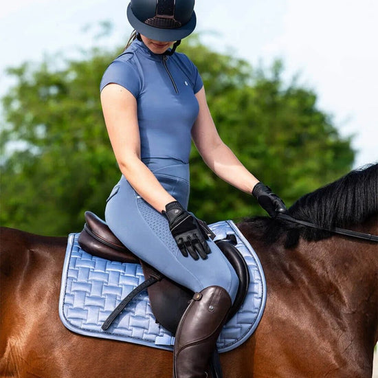 Person in blue qhp training equestrian attire sitting on a horse with a blue saddle pad equestrian fashion outfitters