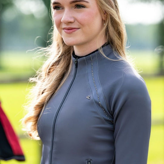Woman wearing a gray long-sleeve top outdoors with greenery in the background equestrian fashion outfitters