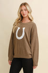 Woman wearing a brown sweater with a white horseshoe design on a beige background - equestrian fashion outfitters