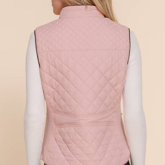Person wearing a pink quilted vest on a beige background equestrian fashion outfitters