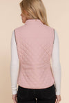Person wearing a pink quilted vest on a beige background equestrian fashion outfitters