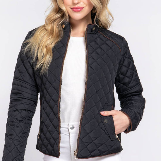 Woman wearing a black quilted jacket on a white background equestrian fashion outfitters