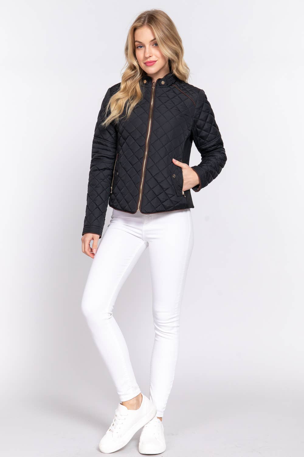 Woman wearing a black quilted jacket and white pants on a light gray background equestrian fashion outfitters
