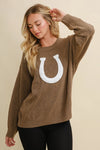 Woman wearing a brown horseshoe pullover sweater with a white horseshoe design on a beige background - equestrian fashion outfitters